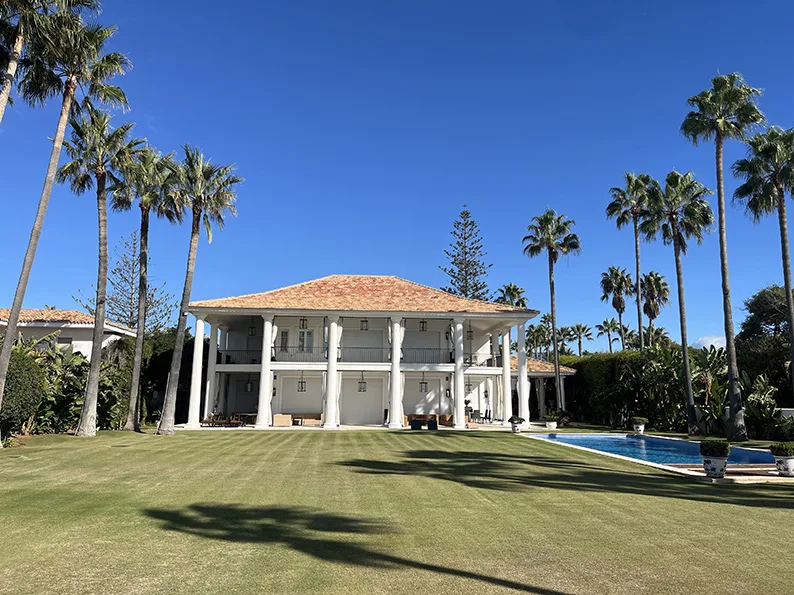 Palmeras altas y césped frente a la vivienda de Cortijo Blanco